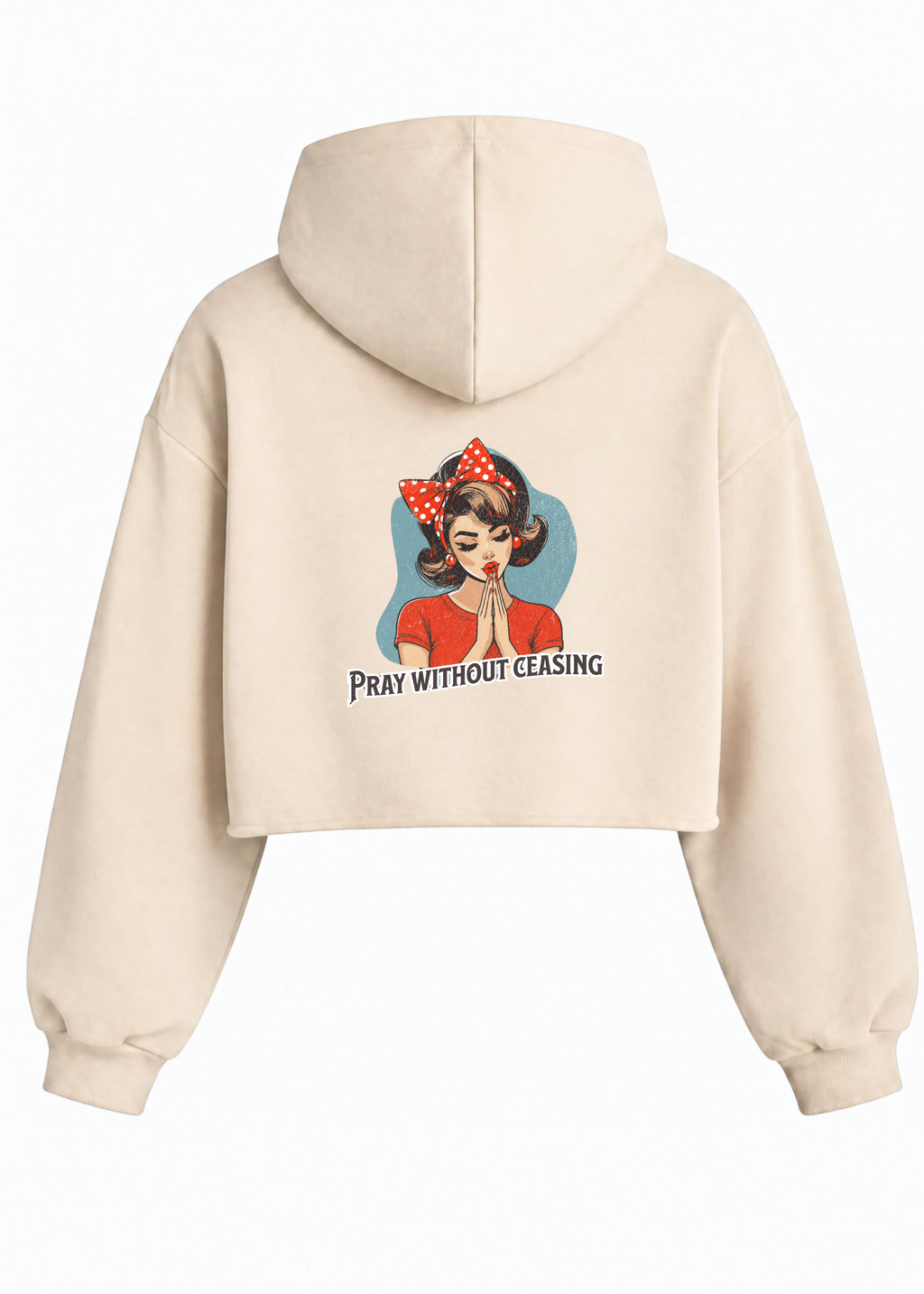 A cream-colored cropped hoodie shown from the back, featuring a graphic of a woman in a red dress and polka-dot headband with the text 'PRAY WITHOUT CEASING' printed below.