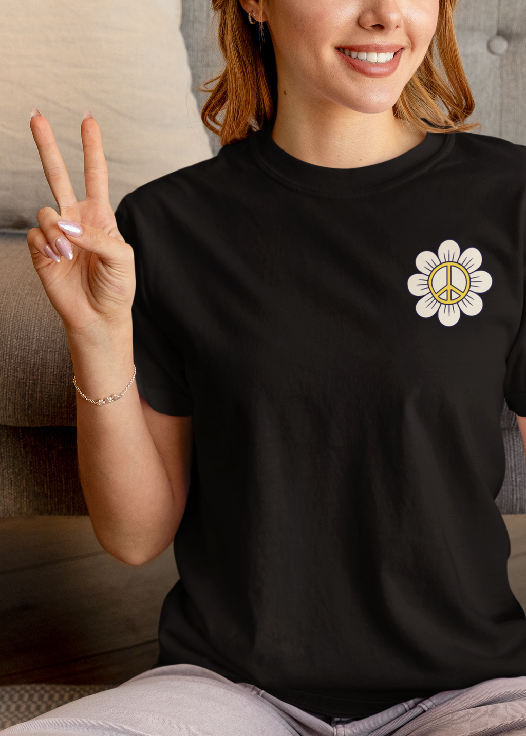 Person wearing a black t-shirt with a white flower design, sitting on the floor in a living room.