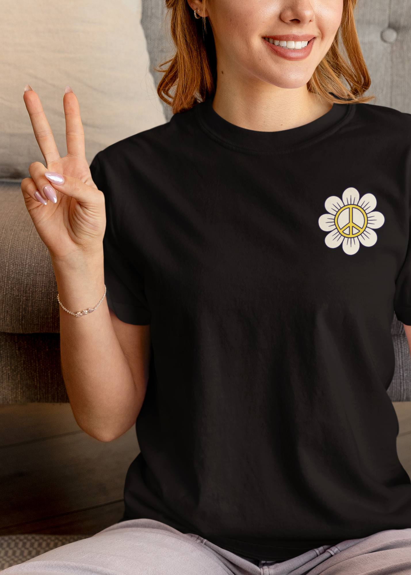 Person wearing a black t-shirt with a white flower design, sitting on the floor in a living room.