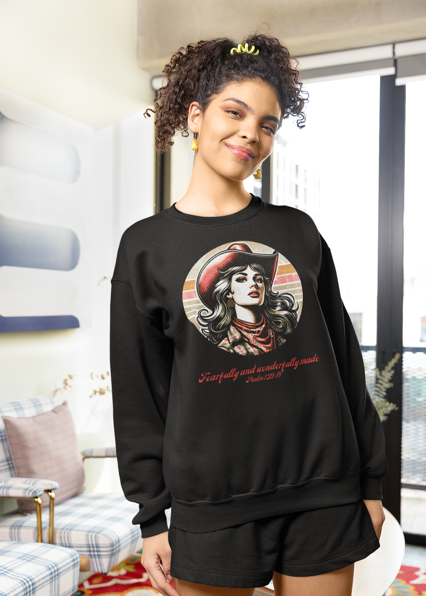 Woman wearing a black sweatshirt with a graphic design in a living room.
