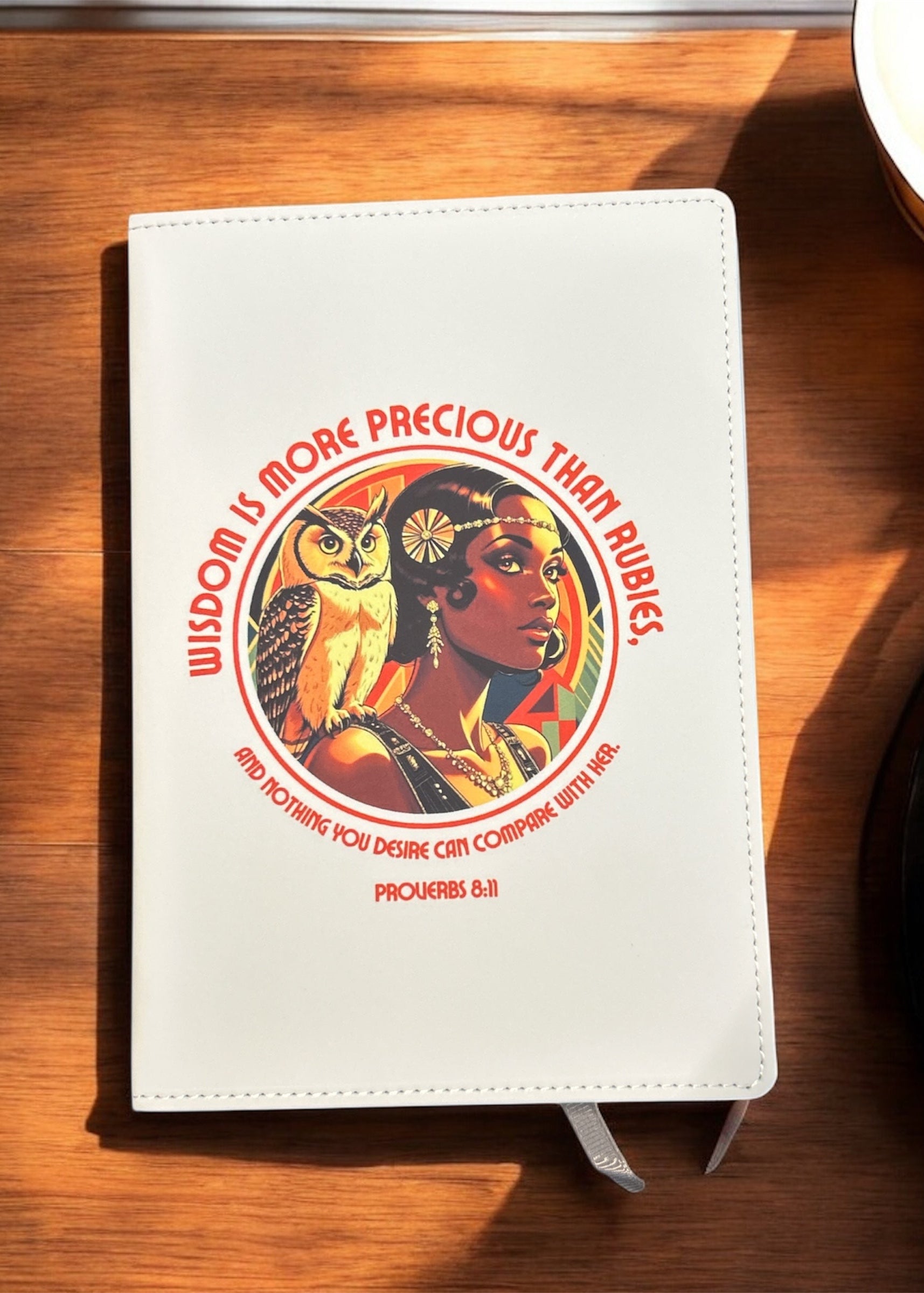 White notebook with a colorful design featuring an owl and a person, placed on a wooden surface. 20s Flapper