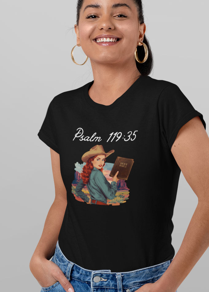 A woman modeling a black graphic T-shirt shown from both front and back against a light gray studio background. The front has white text reading 'Psalm 119:35' above a small illustrated scene, while the back has larger white script text and a small white cross graphic.