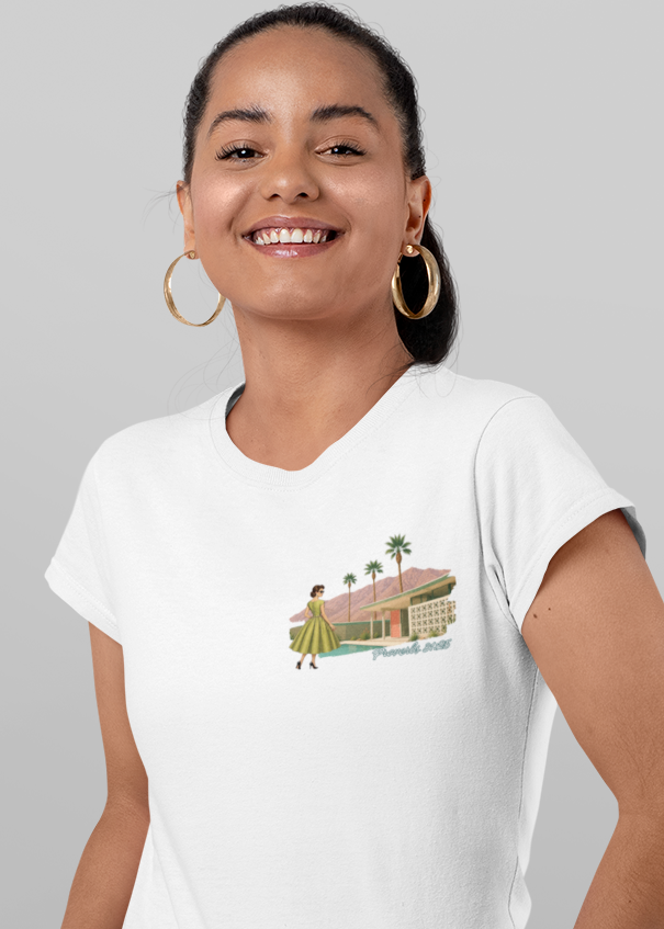 A woman modeling a white graphic t-shirt, shown from both the front and back against a solid gray background. The front features a small graphic of a beach house, while the back displays a larger graphic with the text 'She is CLOTHED IN beauty and glory' and an illustration of a woman in a green dress.